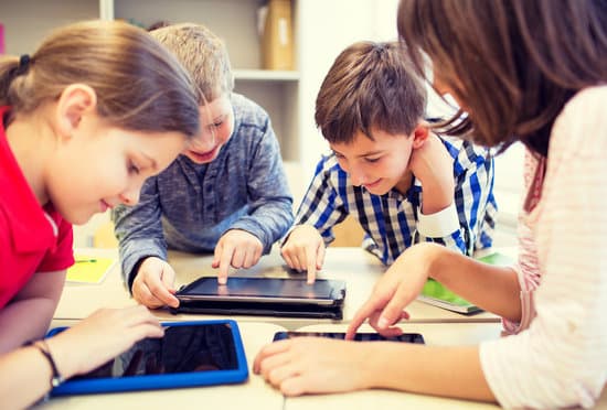 education, elementary school, learning, technology and people concept - group of school kids with tablet pc computer having fun on break in classroom