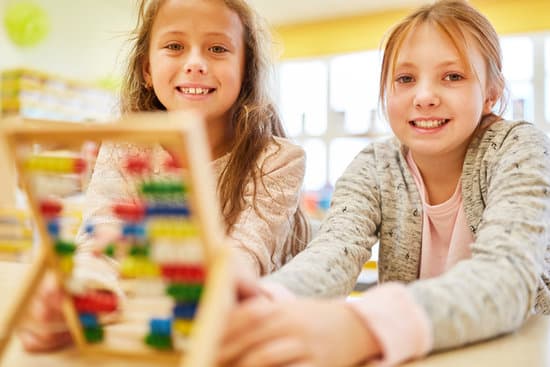 Two girls as elementary school students are calculating with the abacus